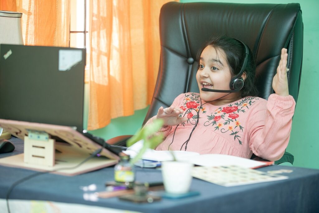 Girl laughing during online session at computer.